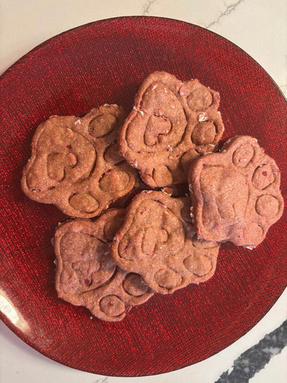 Crunchy Beet-a-licious Paws organic dog treats made with beets and peanut butter in paw shapes on red plate