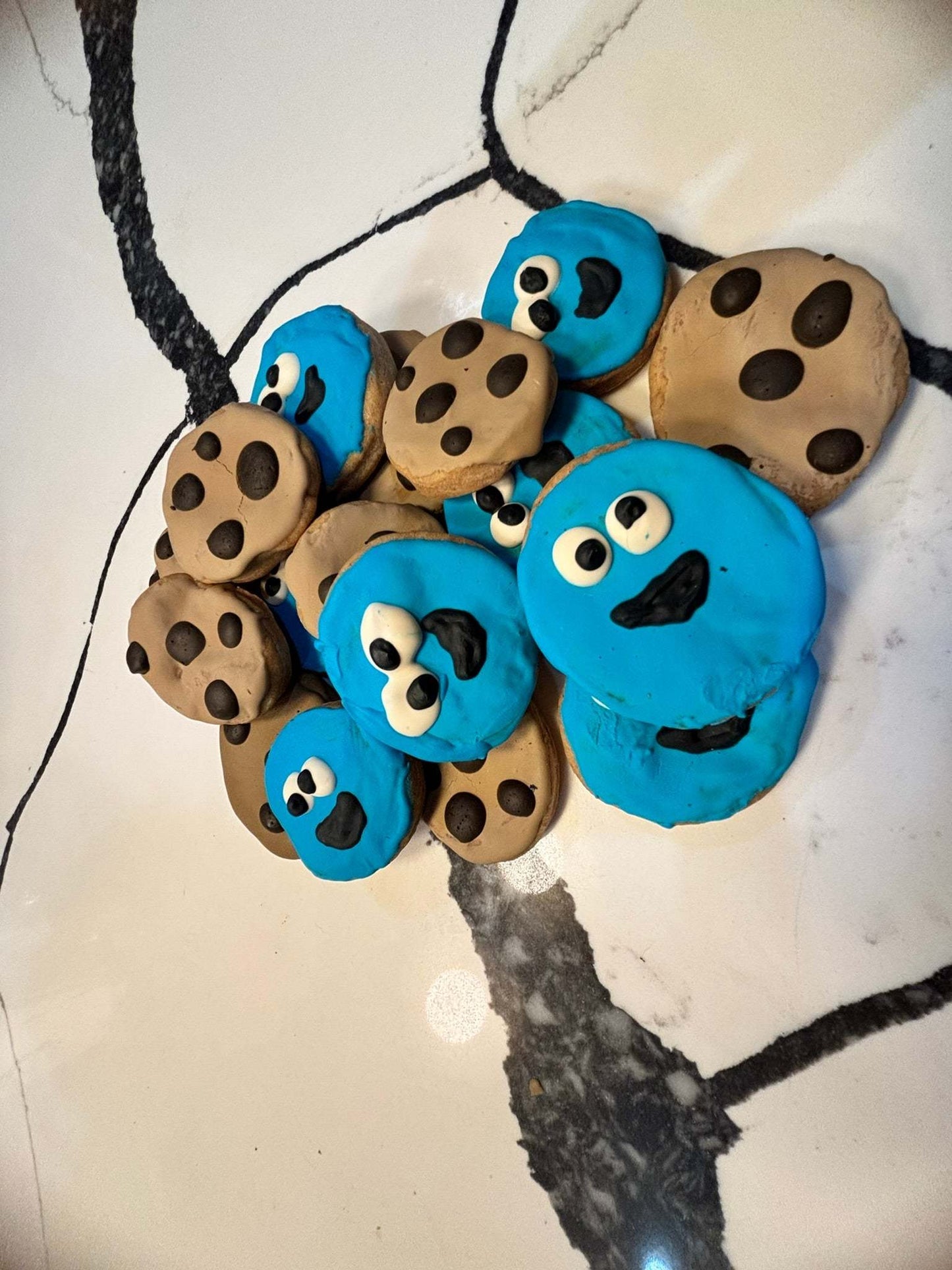 Organic peanut butter dog cookies decorated as Cookie Monster and chocolate chip cookies on marble surface