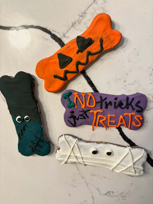Halloween peanut butter dog cookies shaped like pumpkins, ghosts, and bats on a festive plate