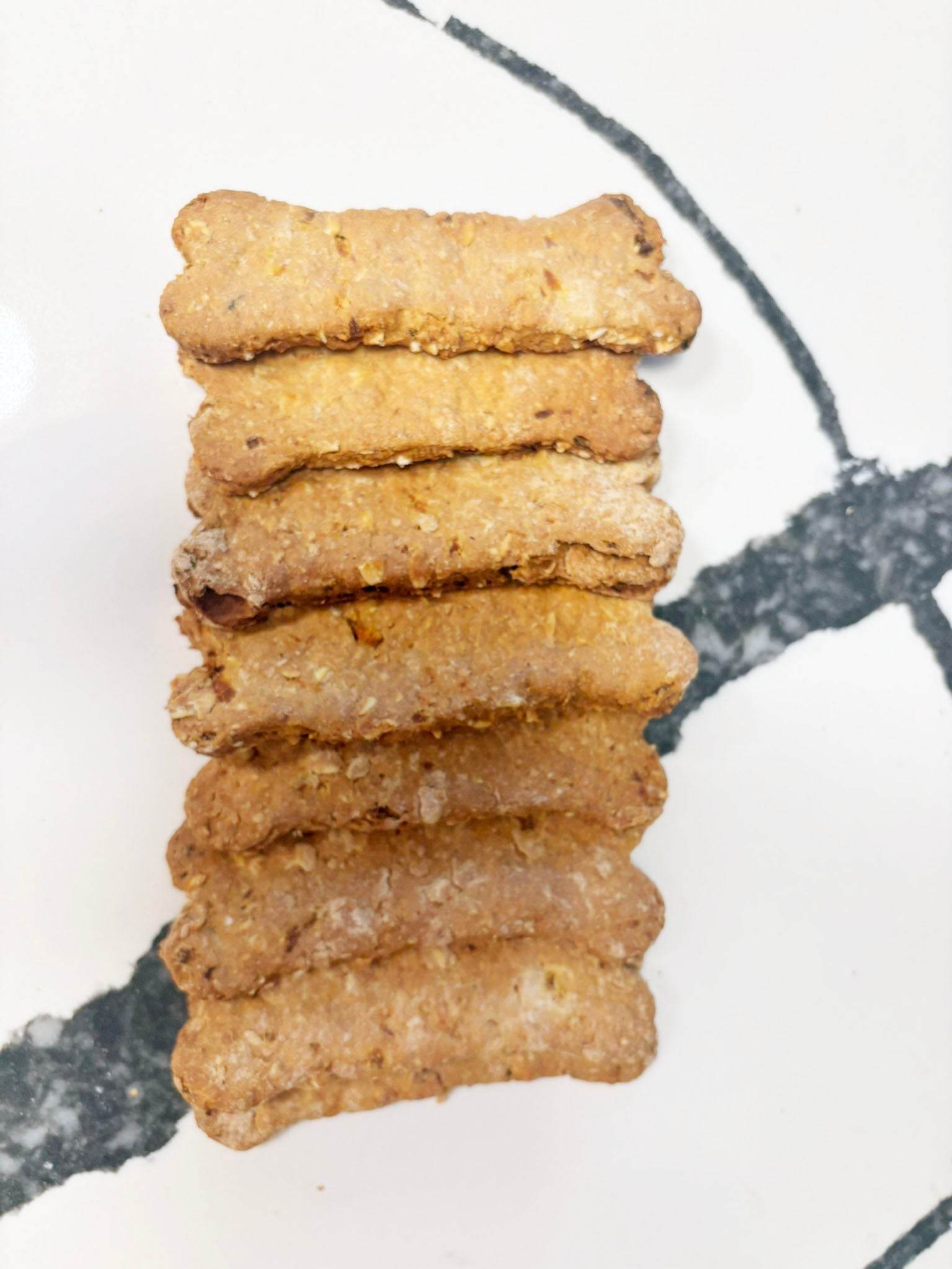 Organic Apple Carrot Bones dog treats stacked on marble surface