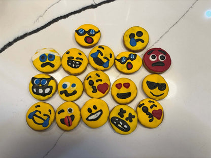 Set of colorful Emoji Peanut Butter Organic Cookies for dogs with various expressive faces on a white marble surface