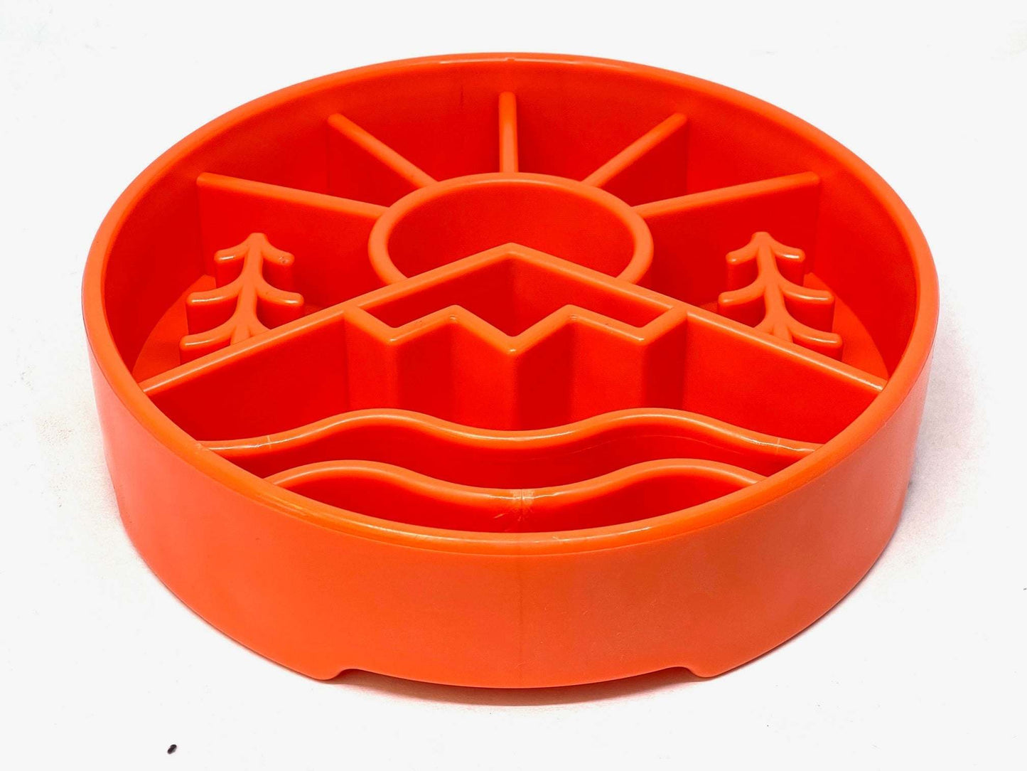 Orange slow feeder dog bowl with raised outdoor design featuring mountains and sun pattern for mental enrichment and slow eating.