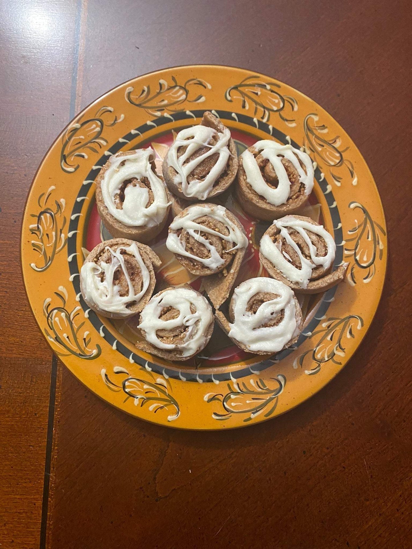 Organic cinnamon buns dog treats with white icing on a decorative plate