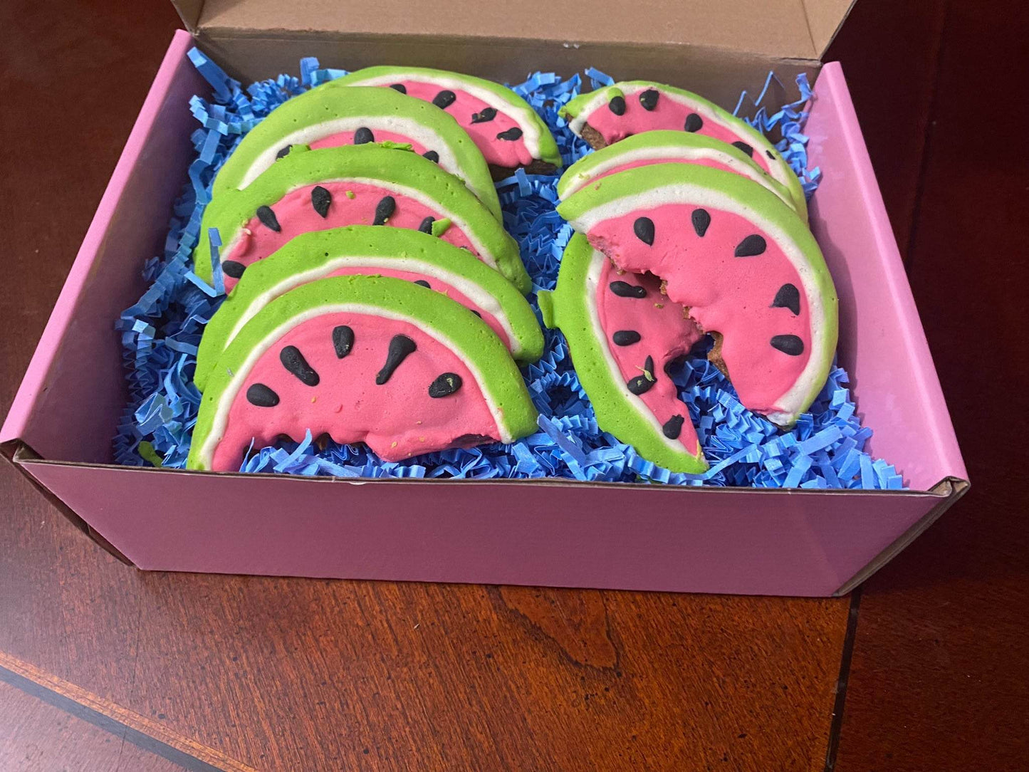 Box of organic watermelon-shaped dog cookies with peanut butter flavor on blue paper filler