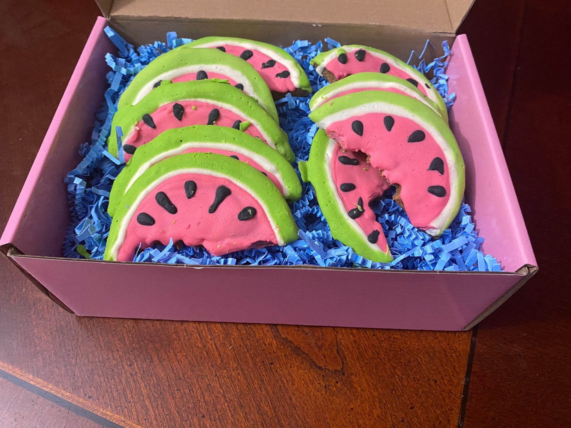 Box of organic watermelon-shaped dog cookies with peanut butter flavor on blue paper filler