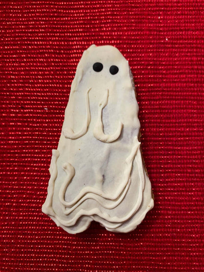 Organic Halloween ghost-shaped dog cookie on red background