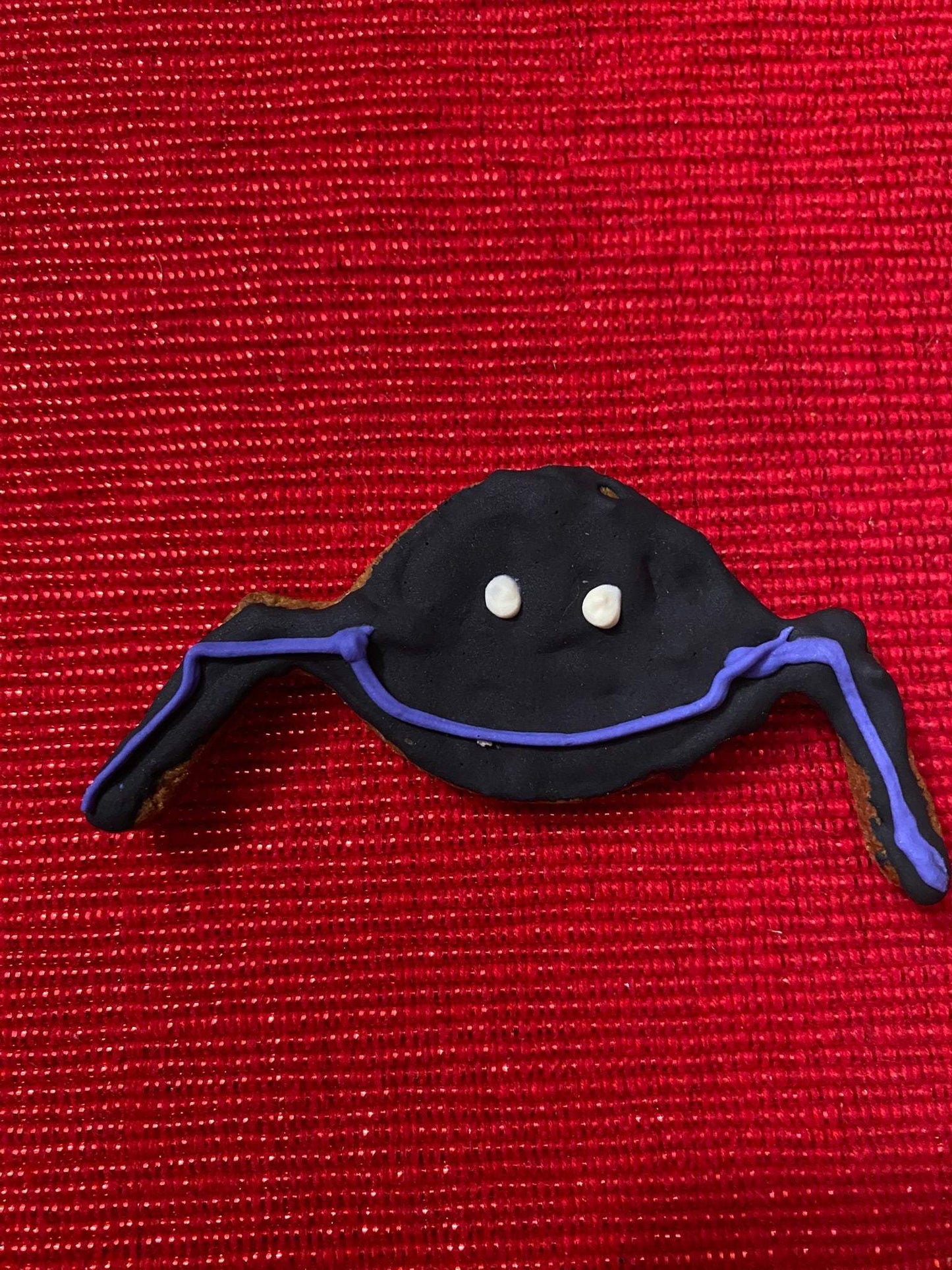 Organic Halloween dog cookie shaped like a ghost with purple accents on red background