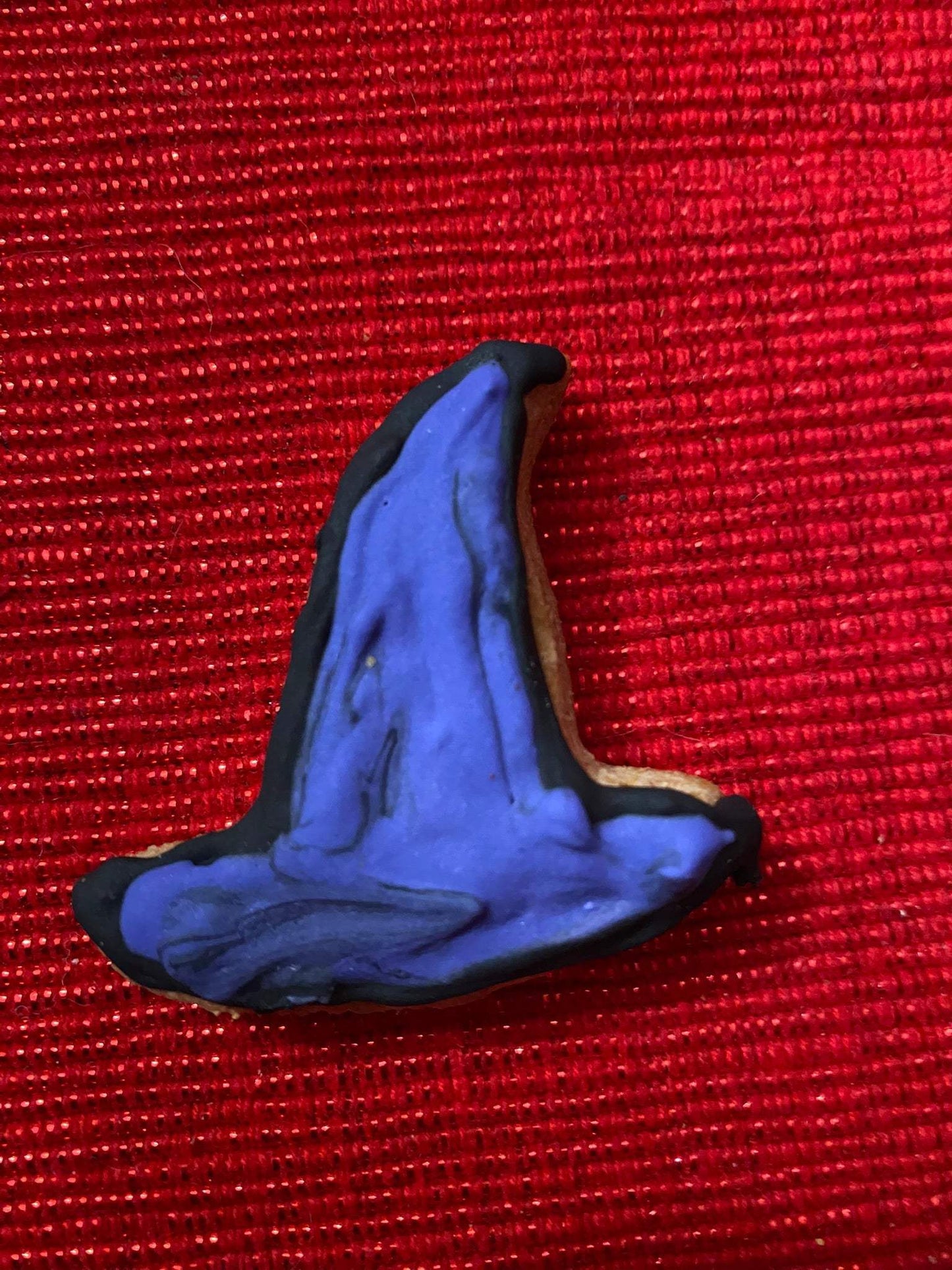 Organic Halloween dog cookie shaped like a purple witch hat with black trim on red background