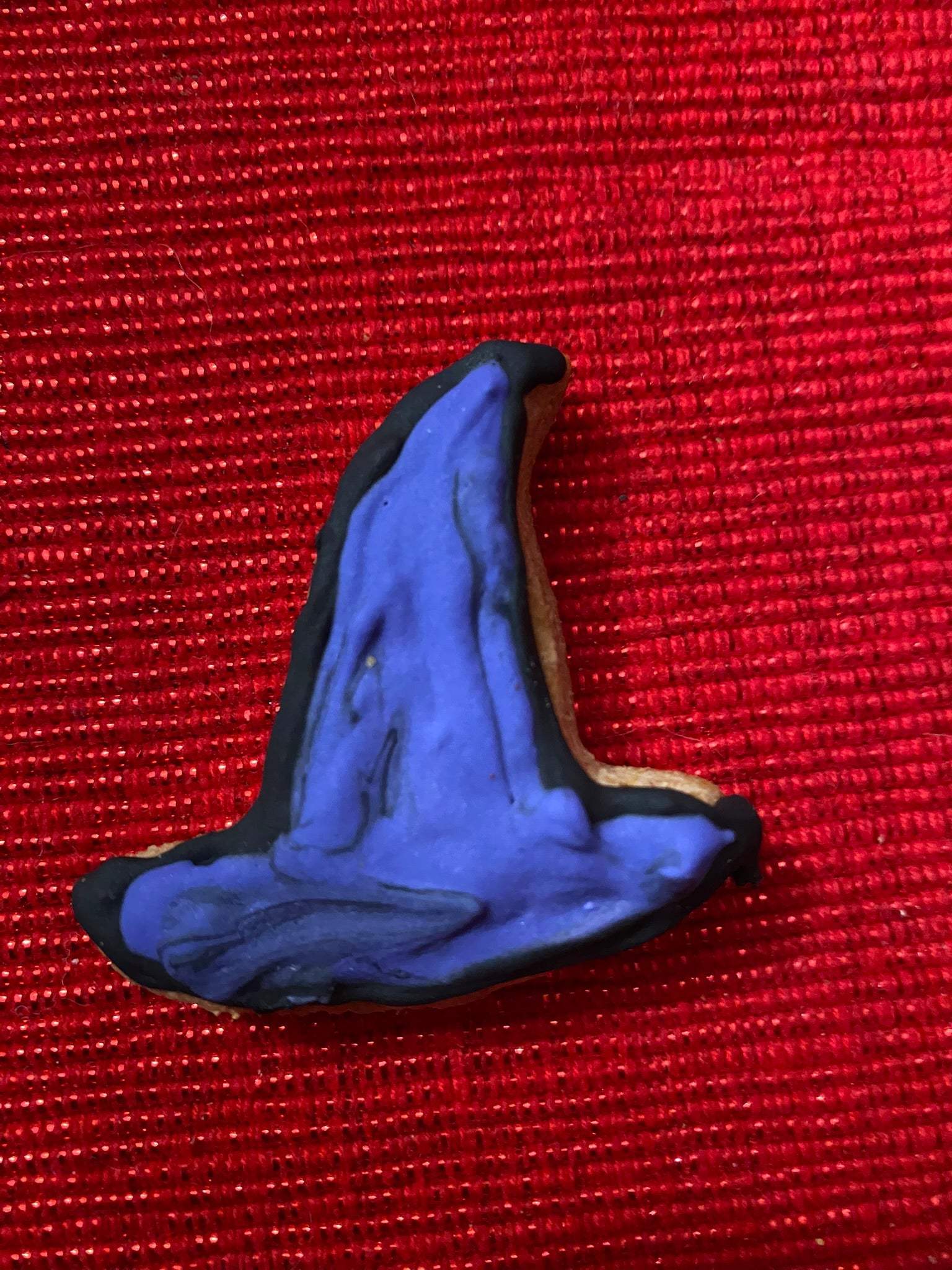 Organic Halloween dog cookie shaped like a purple witch hat with black trim on red background