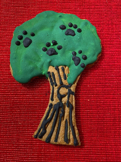 Organic dinosaur-shaped dog cookie decorated green and brown with paw print details on red background