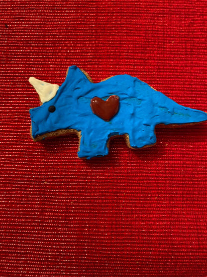 Blue dinosaur-shaped organic dog cookie with a heart decoration on red textured background Dinosaurs Organic Dog Cookie Box