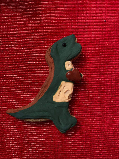 Dinosaur-shaped organic dog cookie with natural ingredients on red background