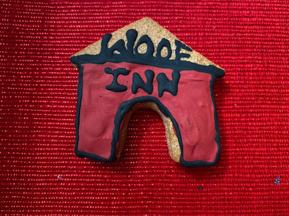 Organic dog cookie shaped like a doghouse with red and black icing on a red textured background from Dog Life Organic Dog Cookie Box