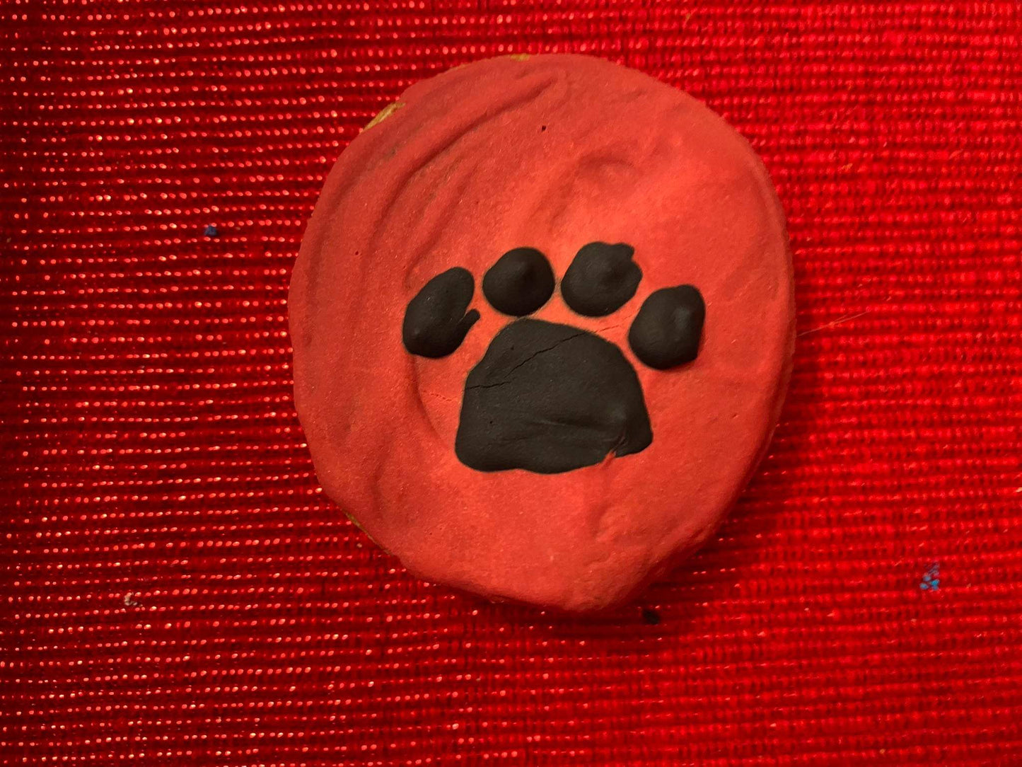 Organic dog cookie with black paw print on red background from Dog Life Organic Dog Cookie Box