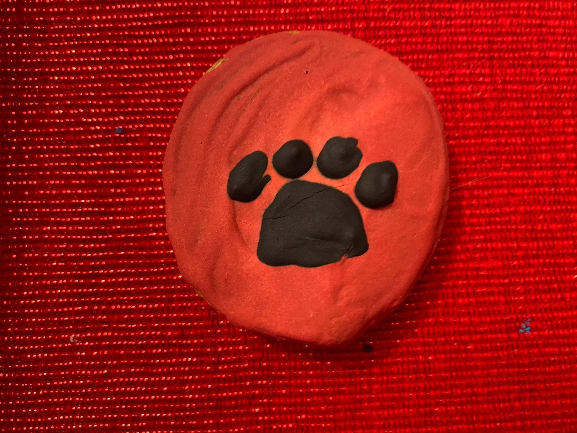 Organic dog cookie with black paw print on red background from Dog Life Organic Dog Cookie Box
