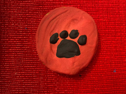 Organic dog cookie with black paw print on red background from Dog Life Organic Dog Cookie Box