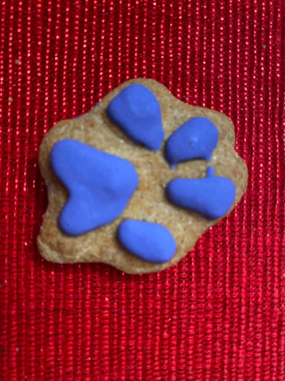 Organic dog cookie shaped like a paw print with blue icing on red background from Dog Life Organic Dog Cookie Box