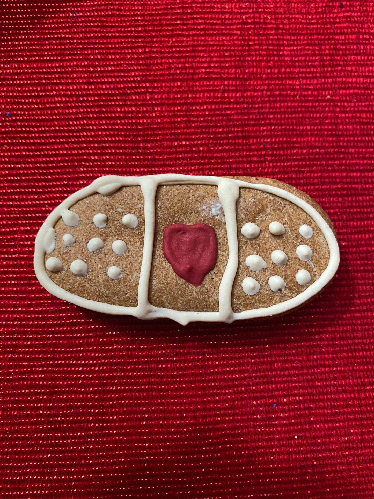 Organic peanut butter dog cookie shaped like a bandage from Get Well Organic Dog Cookie Box on red background