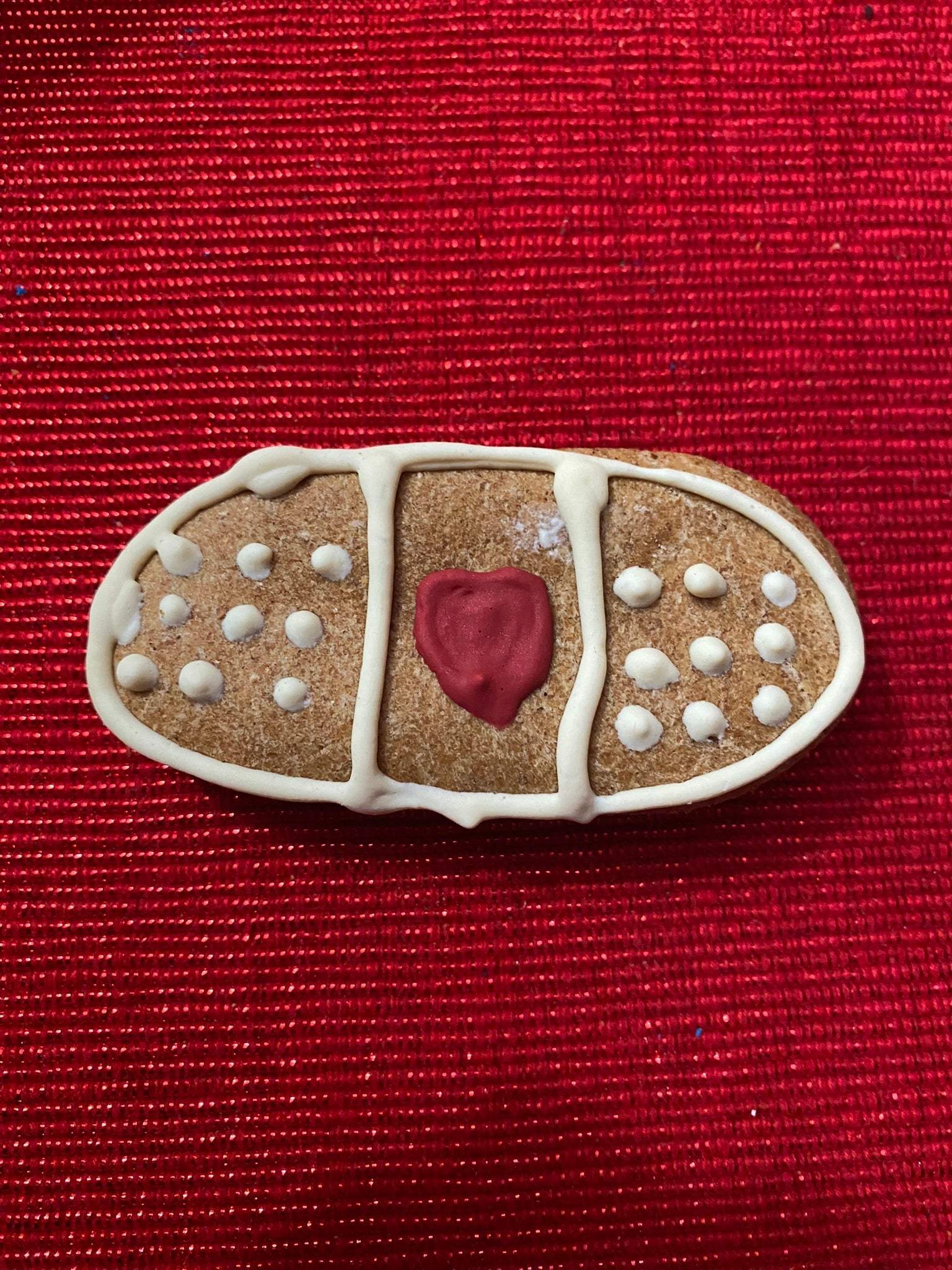 Organic peanut butter dog cookie shaped like a bandage from Get Well Organic Dog Cookie Box on red background