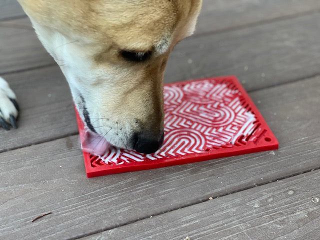 Dog licking red heart-designed love eMat enrichment lick mat for calming and slow feeding