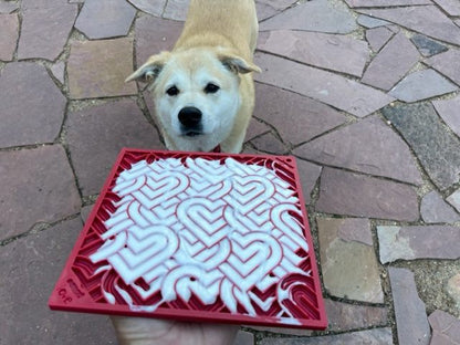 Red heart design Love eMat enrichment lick mat for dogs with textured surface and dog in background