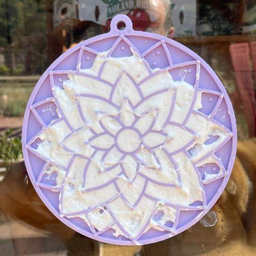 Purple lotus design enrichment lick mat with treats, suction cups attached to window, USA made pet slow feeder.