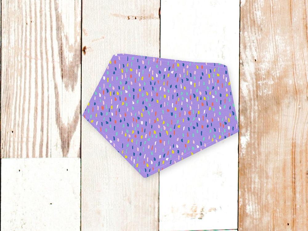 Lavender party dog bandana with colorful confetti pattern and adjustable snap closures on wooden background