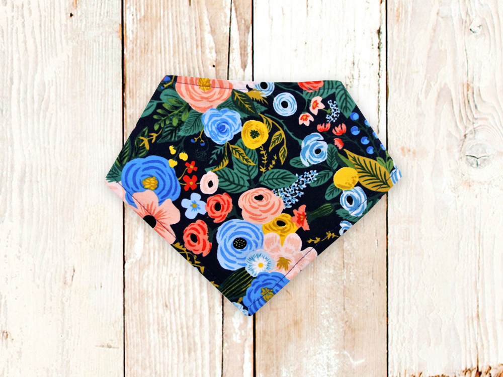 Navy Garden Party dog bandana with floral pattern and adjustable snap closures on white wood background