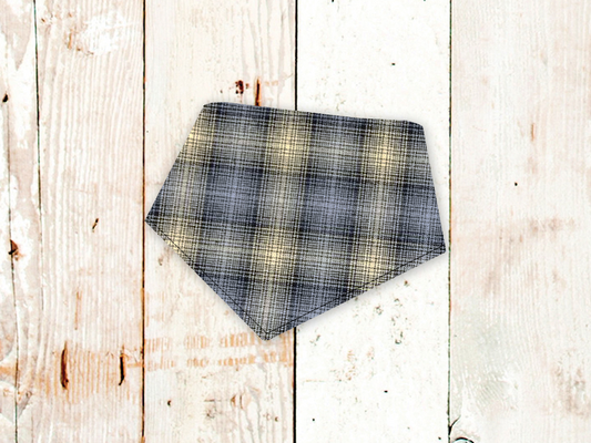 Neutral grey plaid flannel dog bandana with adjustable snap closures on wooden background