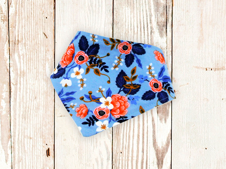 Periwinkle Fleur dog bandana with floral design and adjustable snap closures on wooden background