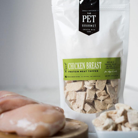 Freeze dried chicken breast dog treat protein meat topper in resealable bag with raw chicken breast nearby