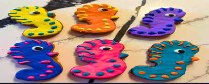 Colorful Pawquatic Ponies seahorse-shaped organic peanut butter dog treats with playful icing spikes and eyes on a marble surface