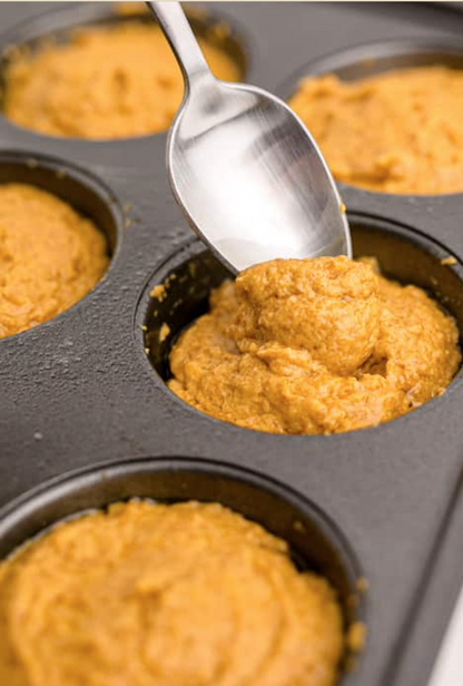 Close-up of organic pumpkin muffin batter being scooped into a baking tray