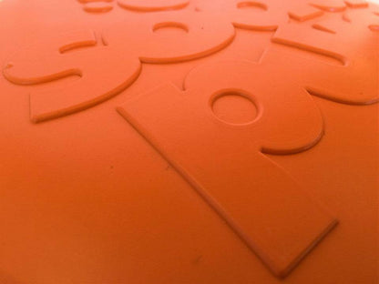 Close-up of orange durable rubber Bottle Top Flyer dog frisbee with embossed design