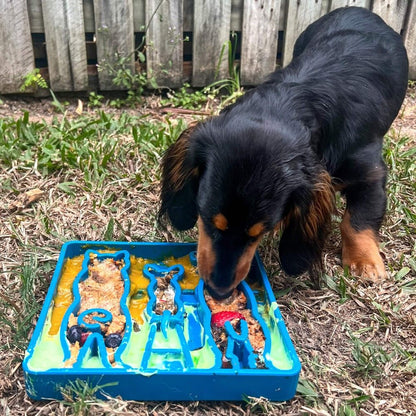 Puppy eating from blue Waiting Dogs Design eTray slow feeder tray with raised ridges outdoors on grass