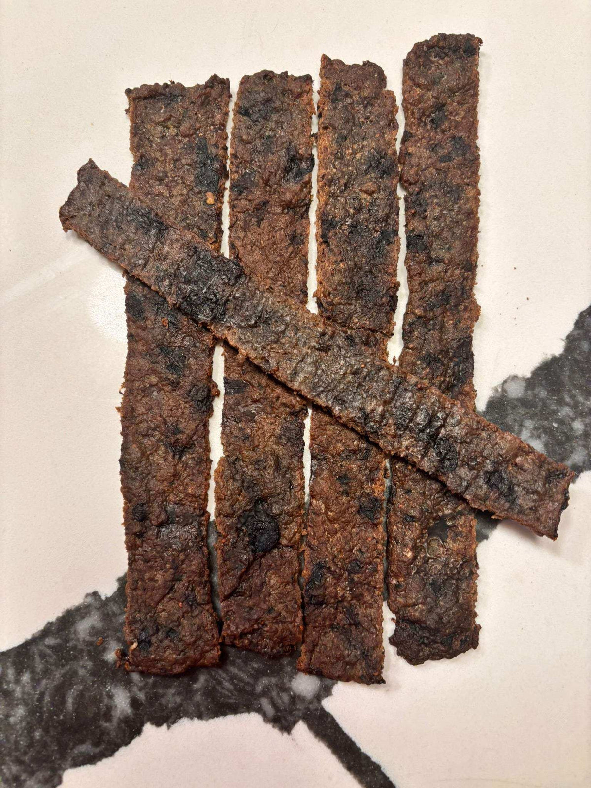 Blueberry Beef Jerky strips in dark brown color with a chewy texture arranged neatly on a surface