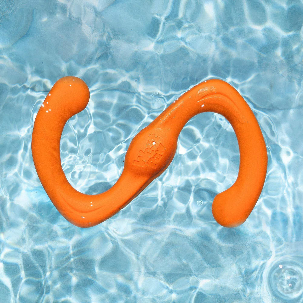 Bumi durable flexible orange S-shaped dog toy made of thermoplastic rubber floating in clear water