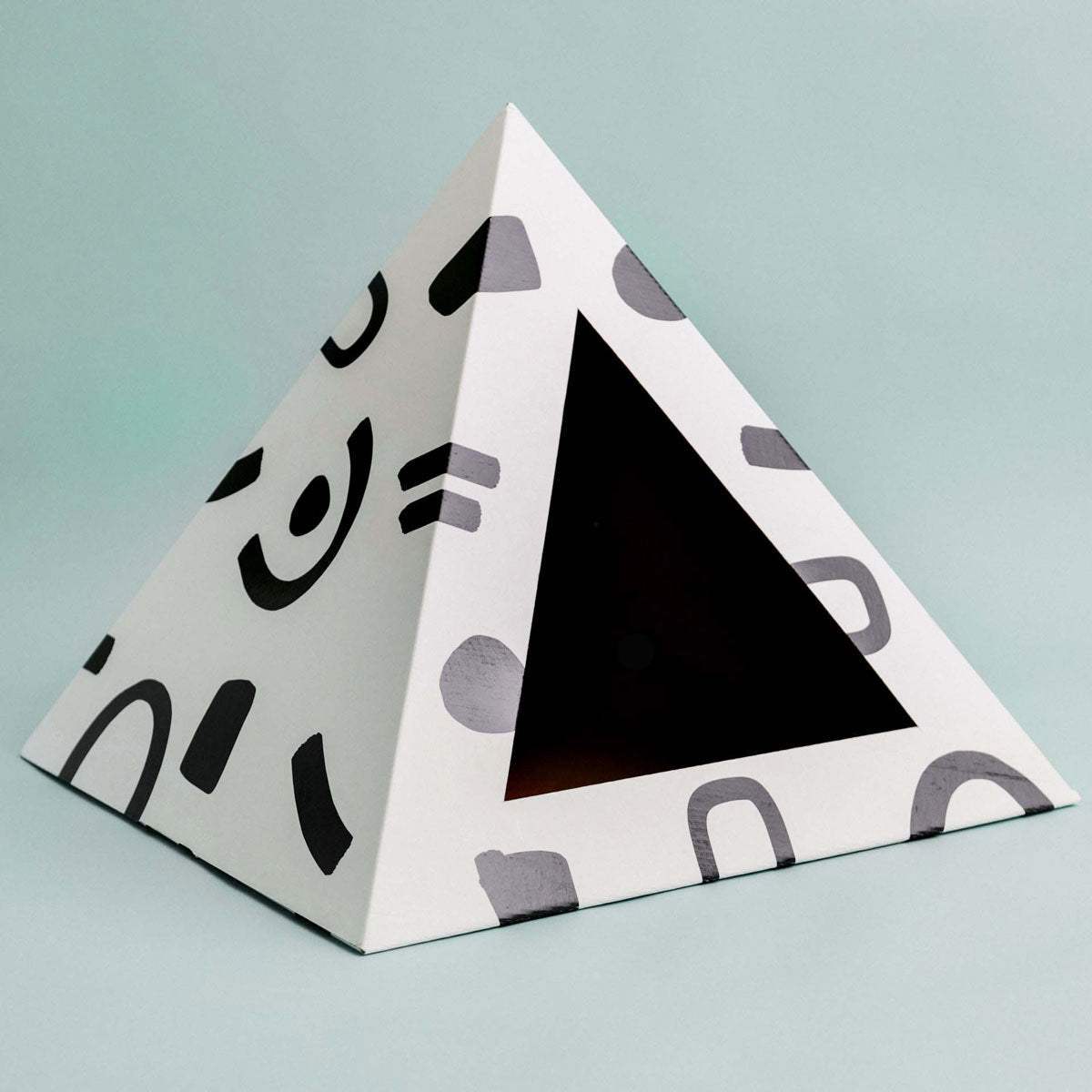Modern artistic cardboard cat pyramid with geometric cutout for cozy cat hideaway