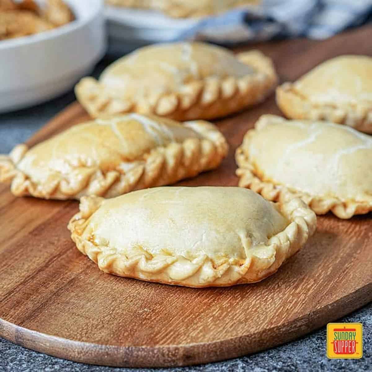 Handmade organic beef EmPAWnadas dog treats with soft whole-wheat pastry on wooden board