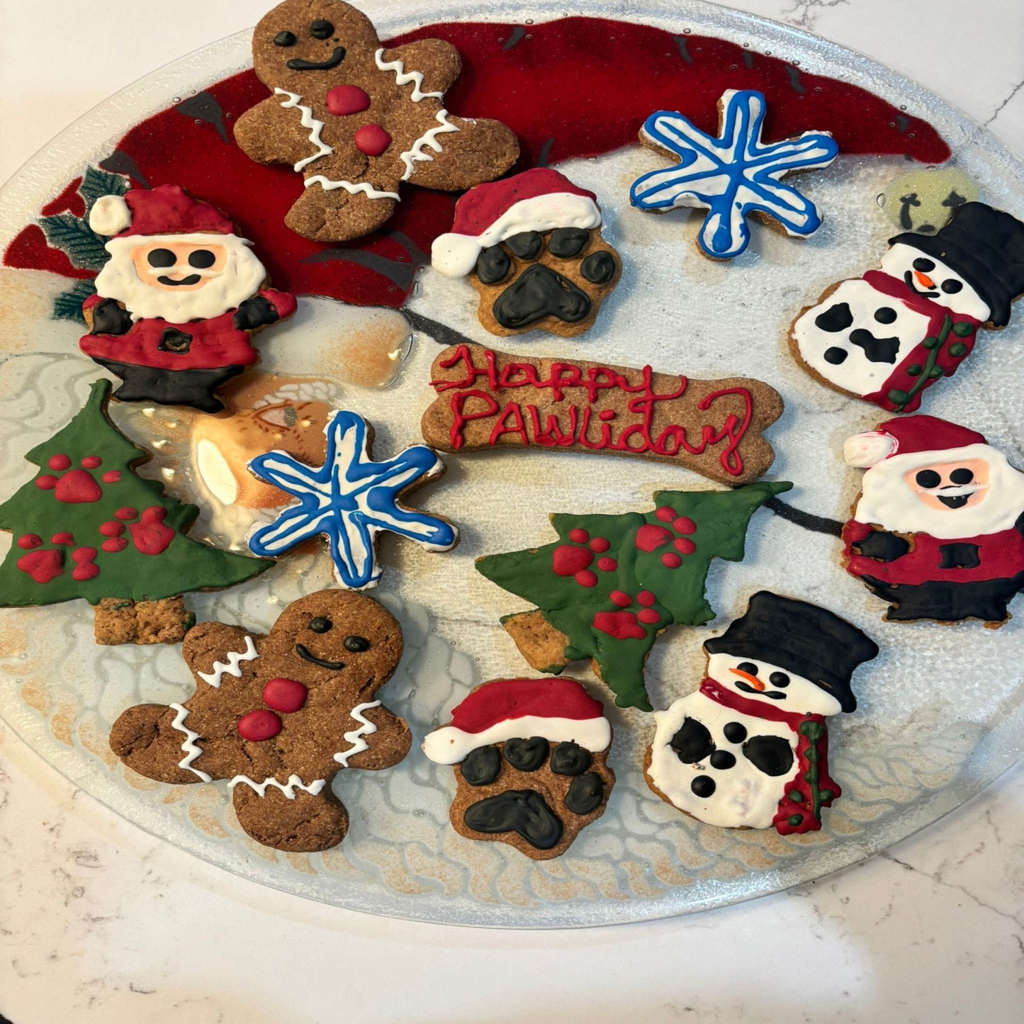 Whimsical Organic Christmas holiday dog cookies with festive shapes and dog-safe icing on a glass plate