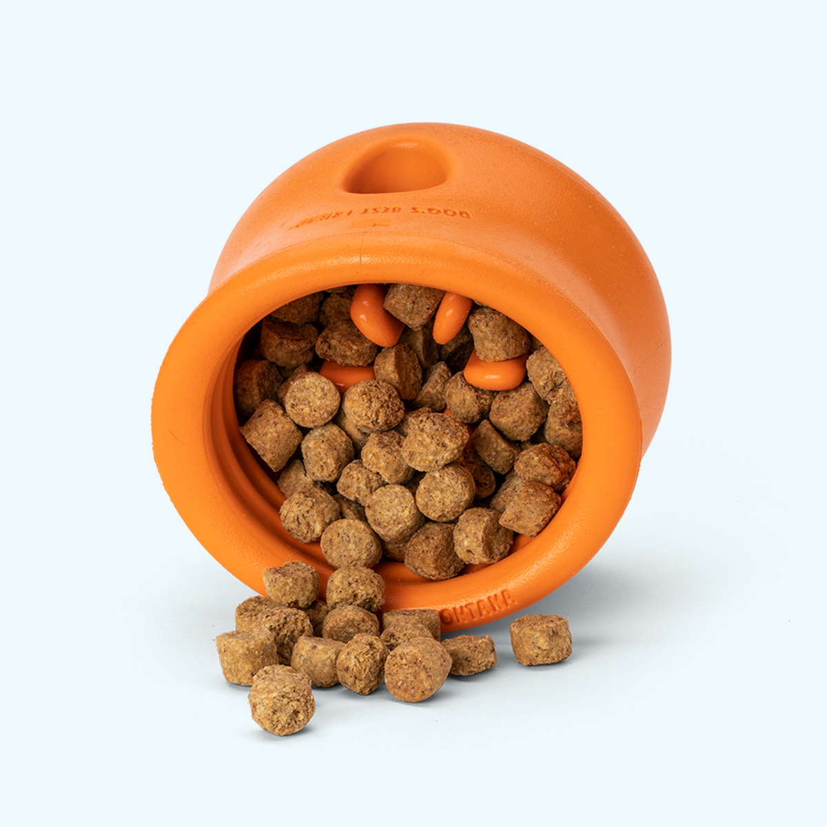 Orange customizable puzzle and treat toy made of rubber with dog kibble inside and spilling out, designed for mental stimulation