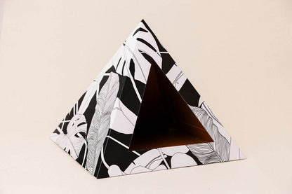 Dark Paradise Cardboard cat pyramid with black and white leaf design, cozy recycled cardboard hideaway for cats.