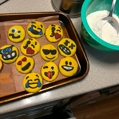 Tray of colorful handmade emoji peanut butter organic dog cookies on a kitchen countertop with mixing bowl and spoon nearby