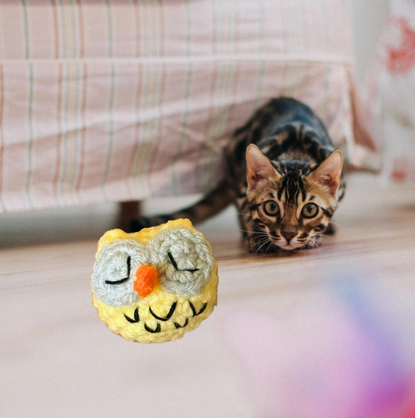Yellow handmade owl-shaped lightweight catnip toy Yolk the owl with a Bengal cat playing in the background
