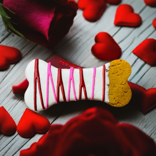 Dipped Bones peanut butter dog treat with yogurt icing decorated for Valentine's Day surrounded by red hearts and roses