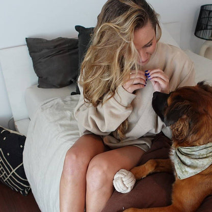 Woman playing with dog using indestructible hemp rope ball toy indoors