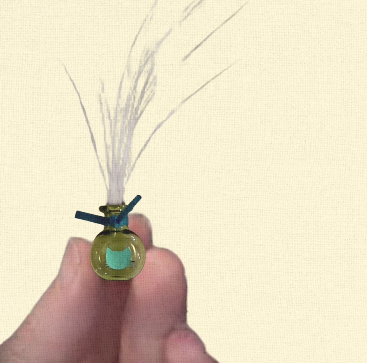 Small green glass whisker vase with delicate dried grass, held between fingers, Whisker Vases keepsake for cat lovers