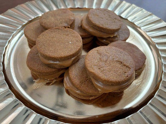 Peanut Butter Macarons with light brown crunchy cookies and creamy peanut butter filling stacked on a silver plate