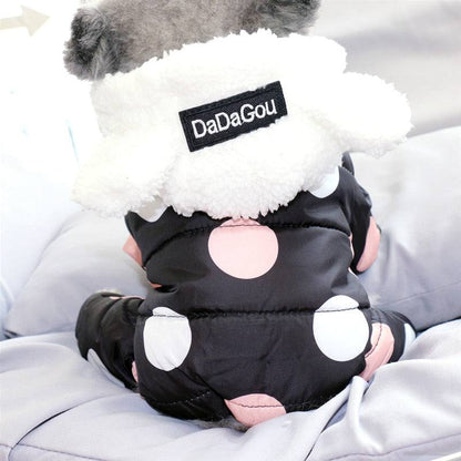 Small dog wearing black waterproof snowsuit jumpsuit with large pink and white polka dots and fleece-lined hood with ears