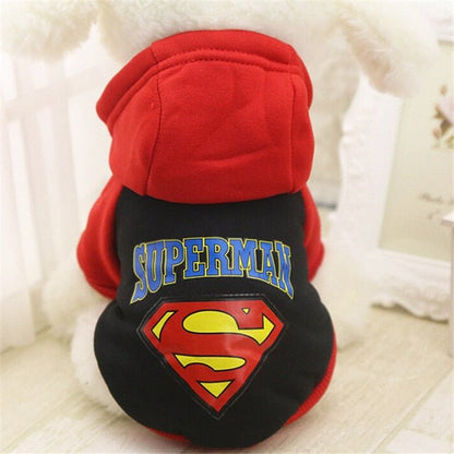 Small dog wearing red and black cartoon hoodie sweater with Superman logo on back